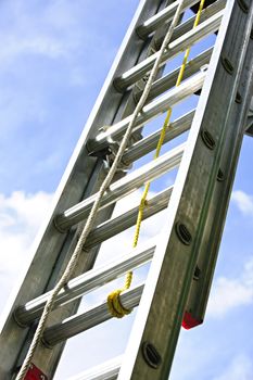 Closeup of construction aluminum extension ladder against blue sky