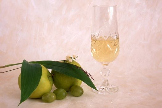 A glass of white wine with fruits on painted background