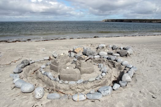 a sandcastle made with stones and sand on an irish shore