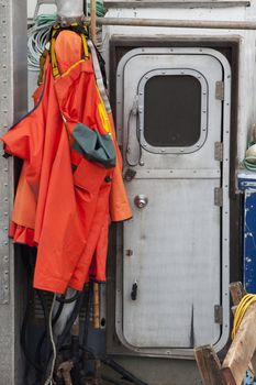 waterproof storm jackets and bibs hanging on fishing boat