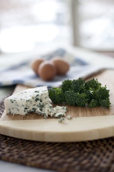 Fresh broccoli, blue cheese, and eggs; ingredients for a quiche.