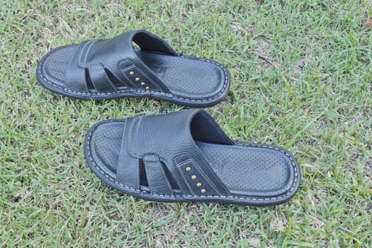 A pair of men black sandals on the grass