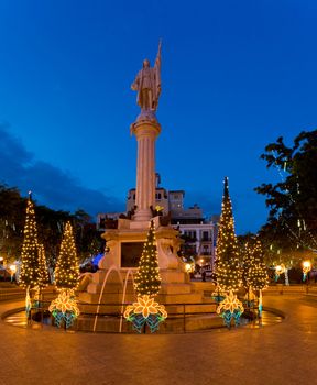 Plaza Colon in old San Juan with statue of Cristobol Colon surrounded by xmas trees and illuminations