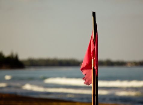 Sun setting lights up red flag signaling danger for swimming in surf