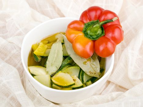 Delicious vegetarian soup made from zucchini and yellow paprika served in white porcelain bowl