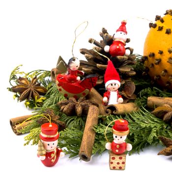 Closeup picture of thuja branches, orange, spices and small wooden figure on white background.