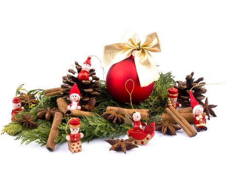 Christmas arrangement of thuja branches, red glass ball, spices and small wooden figure on white background.