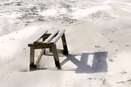 Broken wooden bench in Baltic sea beach. Windy day. The wind blows off sand