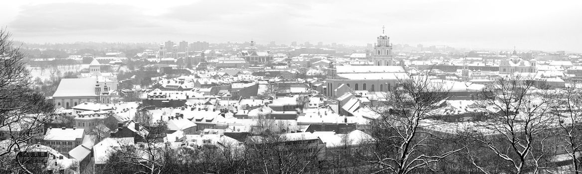 Vilnius old city in december morning. Snow covered roofs and trees.