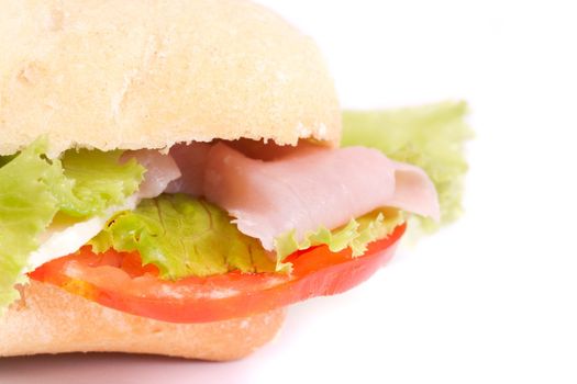 Close view of a fresh tasty ciabatta sandwich with tomato, lettuce, cheese and ham isolated on a white background.