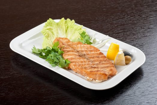 Grilled salmon steak with greens,onion, lemon, lime and olive