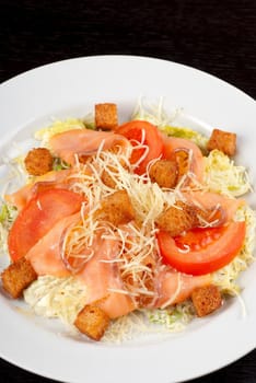 Salad of lettuce, chinese cabbage, tomato, garlic rusk, parmesan cheese, sauce and smoked salmon filet