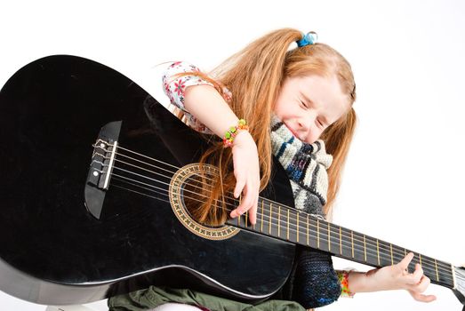 studio shot of pretty little girl playing black acoustic guitar