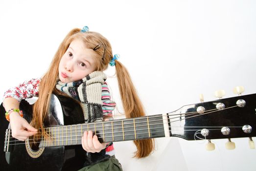 studio shot of pretty little girl playing black acoustic guitar