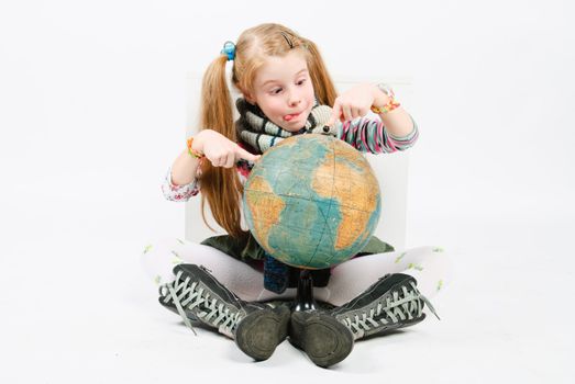 studio shot of pretty little girl staring at the globe