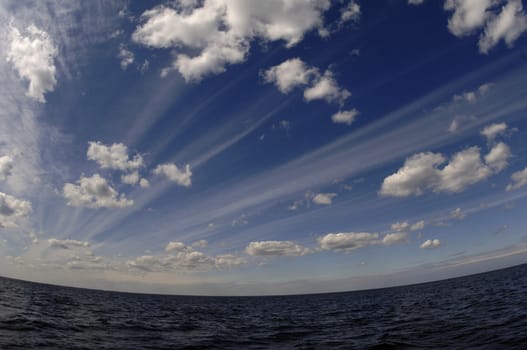 The summer sky over lake. The summer dark blue sky with plumose clouds over lake.