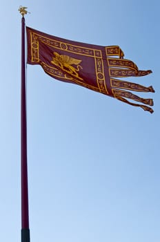 Venetian flag over blue sky in Venice, Italy