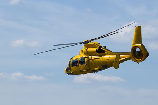 Yellow Helicopter flying in cloudy sky