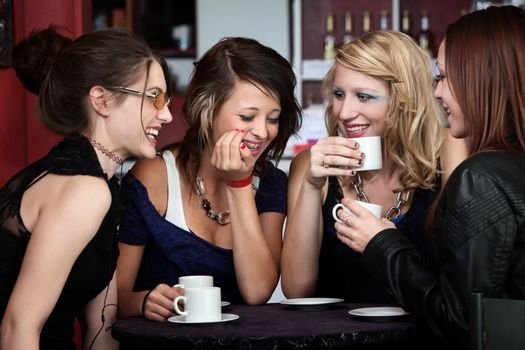 A foursome of pretty girls laughing in a cafe