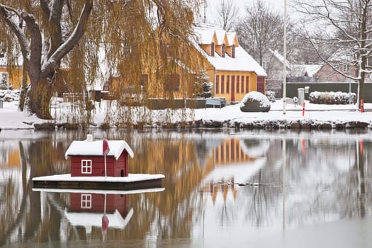 Minature snow covered house floating on a pond