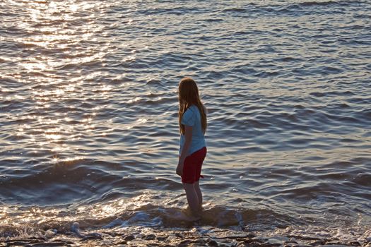 This image shows a girl at sea in the evening sun