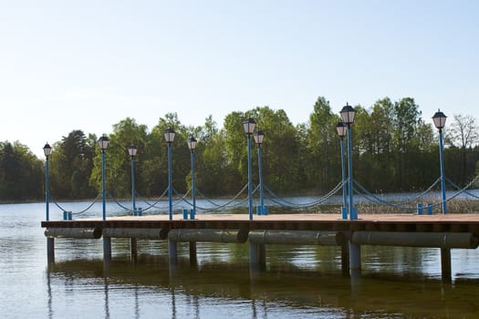 Wooden pier with lanterns on the lake Valdai, Russia.