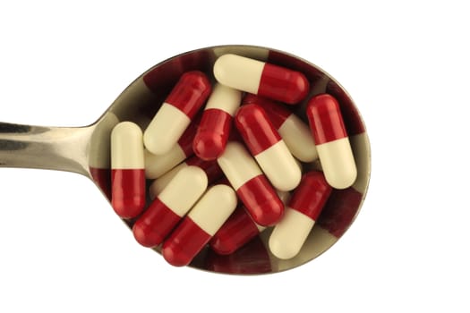 Spoon with pills isolated in white