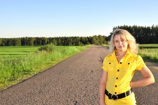 Young smiling woman in Yellow catching a car on empty road