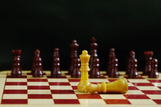 King fallen at the feet of queen in a chess game