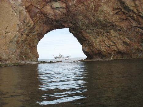 perce rock hole with a boat crossing, in Gaspesie, Quebec