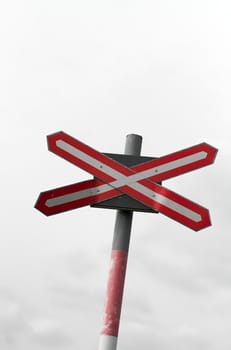 Railway crossing sign with grey sky