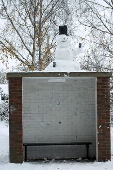 Snow man on bus stop drinking beer