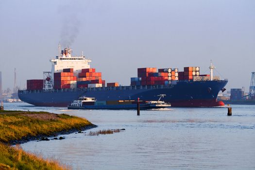 Big container ship on the river leaving port by evening light