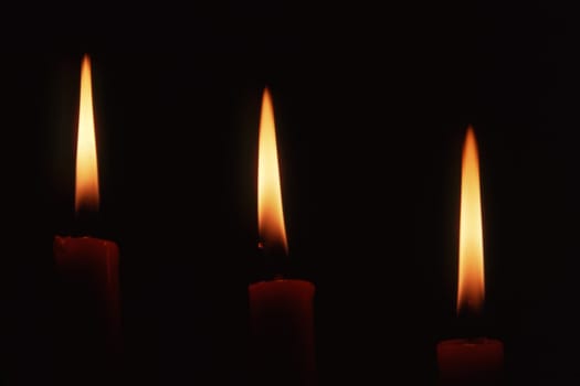 Three candles in dark background
