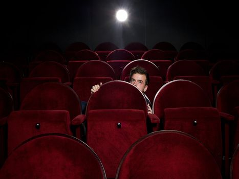 Afraid young man alone in the movie theater