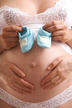 woman`s and man`s  hands on the future baby with baby's bootees