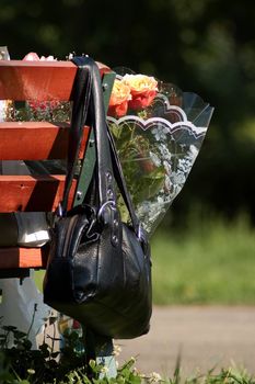 Handbag and bunch of flowers on a park bench