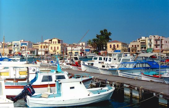 A pier and quoddy boats are against the picturesque greek town