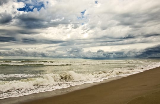 empty beach diring a storm with heavy clouds and waves