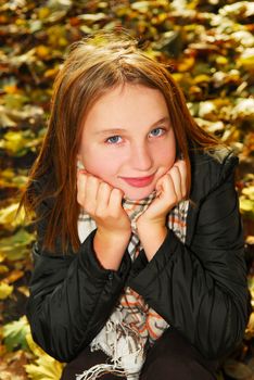 Portrait of a beautiful teenage girl in a fall park with fallen leaves