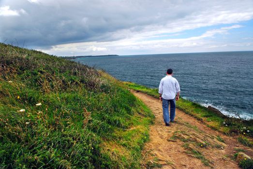 A man walking on a hiking trail along the coast of Brittany, France