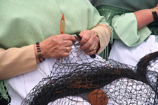 Woman showing traditional skill of repairing fishingnet