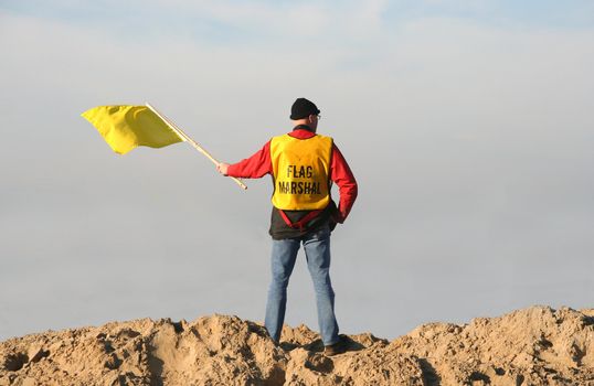 Flag marshal waving the yellow flag at a motorcross