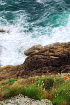 Looking down a cliff onto stormy ocean at the rocky coast of Brittany, France