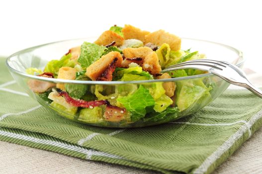 Fresh caesar salad with croutons and bacon bits served in a glass bowl