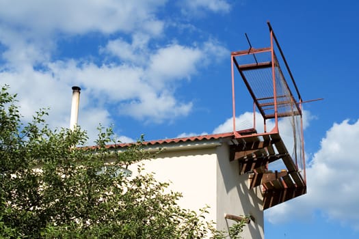 part of rural house. roof with a pipe and ruined dovecote on sky bacground.