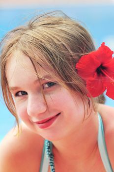 Portrait of a young girl on tropical beach with red flower