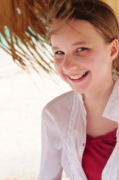 Portrait of a young girl on tropical beach under umbrella