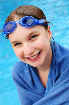 Teenage girl at the swimming pool wrapped in blue towel