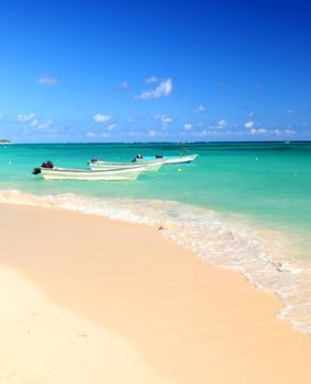 Fishing boats in Caribbean sea anchored near sandy beach